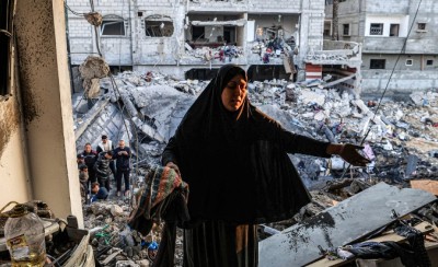 2023年12月19日，位于加沙地带南部的拉法，一名妇女正在检查巴勒斯坦记者阿德尔· 佐罗布（Adel Zorob）曾经的居所，他已在以色列的一次夜间轰炸中丧生。图片来源：法新社/Mahmud HAMS