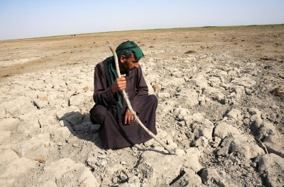 Мужчина из числа болотных арабов смотрит на сухую землю, которая была под водой, около Чибайиша в южном Ираке © REUTERS