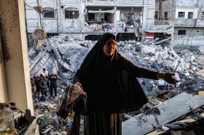 2023年12月19日，位于加沙地带南部的拉法，一名妇女正在检查巴勒斯坦记者阿德尔· 佐罗布（Adel Zorob）曾经的居所，他已在以色列的一次夜间轰炸中丧生。图片来源：法新社/Mahmud HAMS