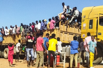 2023年12月16日，因苏丹冲突而流离失所的人们登上了一辆卡车的车斗，这辆卡车行驶在杰济拉州首府瓦德迈达尼的公路上。据法新社记者报道，12月15日，苏丹军方与准军事团体爆发战斗，战火席卷了作为流离失所者援助枢纽的瓦德迈达尼，导致因持续八个月的战争而流离失所的平民不得不再次逃离。© 法新社