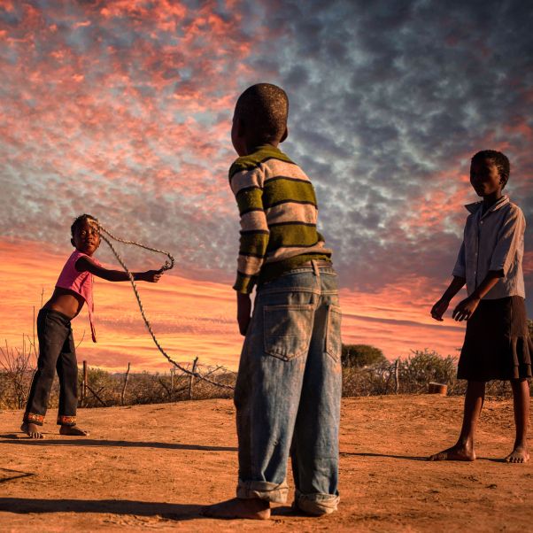 African girls and boy group skipping rope in the yard in front of the house - stock photo. © Getty Images