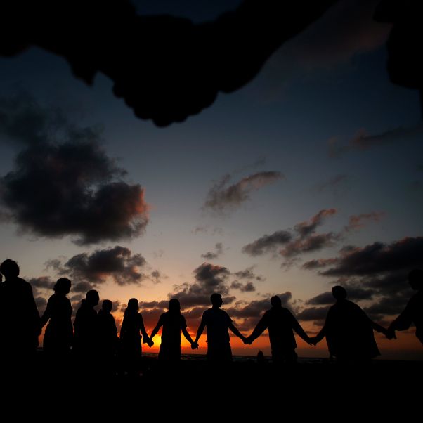 Israeli and foreign participants hold hands as they pray for the entrance of Shabbat during sunset on the beach of the Israeli coastal city of Natanya, Israel. © EPA/Atef Safadi