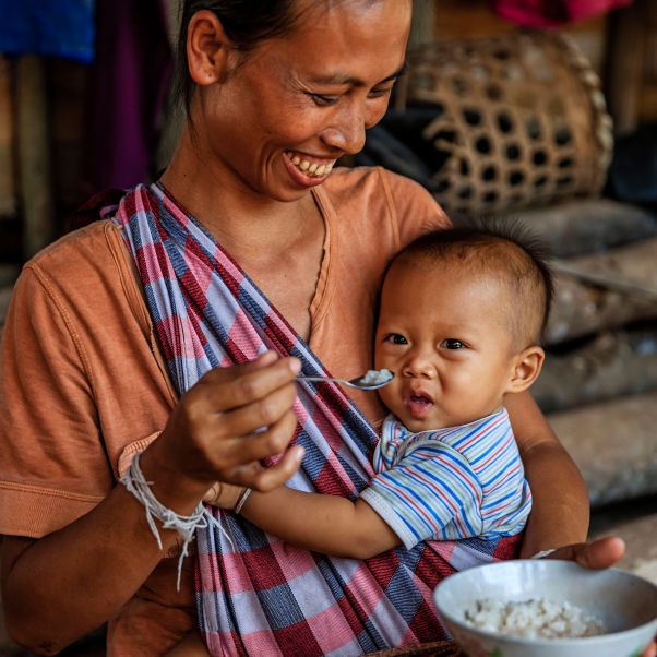 Laotian young mom feeding her baby boy in a village in Northern Laos. © Getty Images