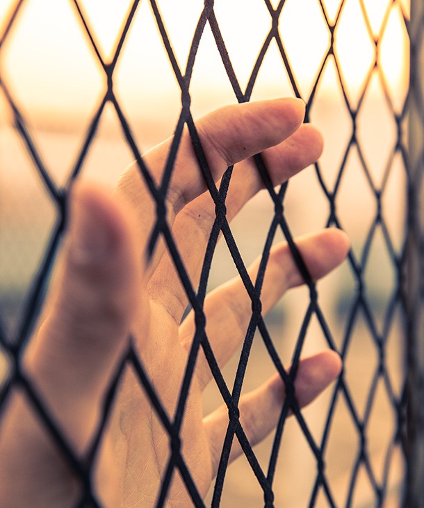 A hand behind a wire fence