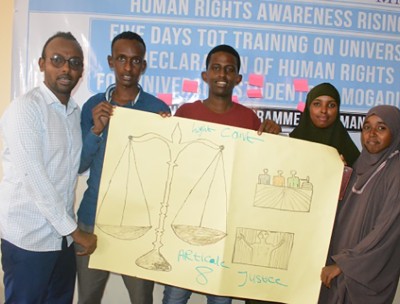 Somali students in the UDHR training project holding up a poster illustrating Article 8 of the Declaration