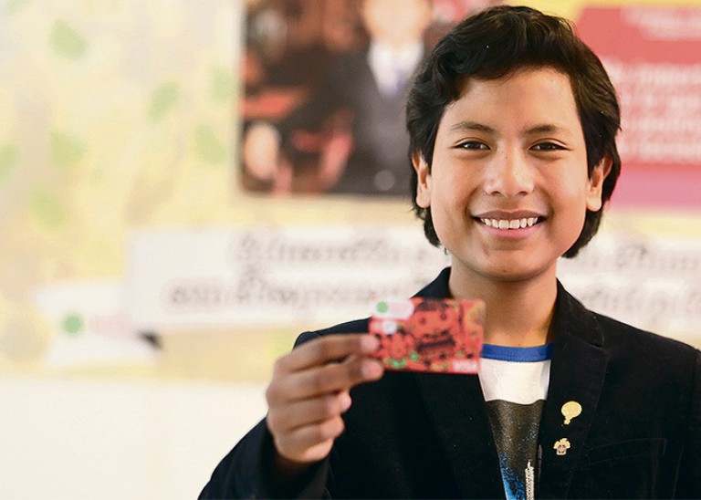 José Quisocala poses with card from bank he established at age seven to help impoverished children. © José Quisocala