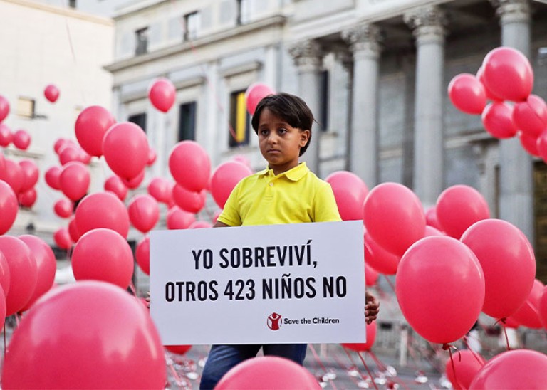 Eight-year-old Syrian refugee Zaid poses for photographers surrounded by balloons while holding a banner that reads, “I survived, 423 other children did not”, during an event organized by Save the Children in Madrid, Spain. EPA/EMILIO NARANJO