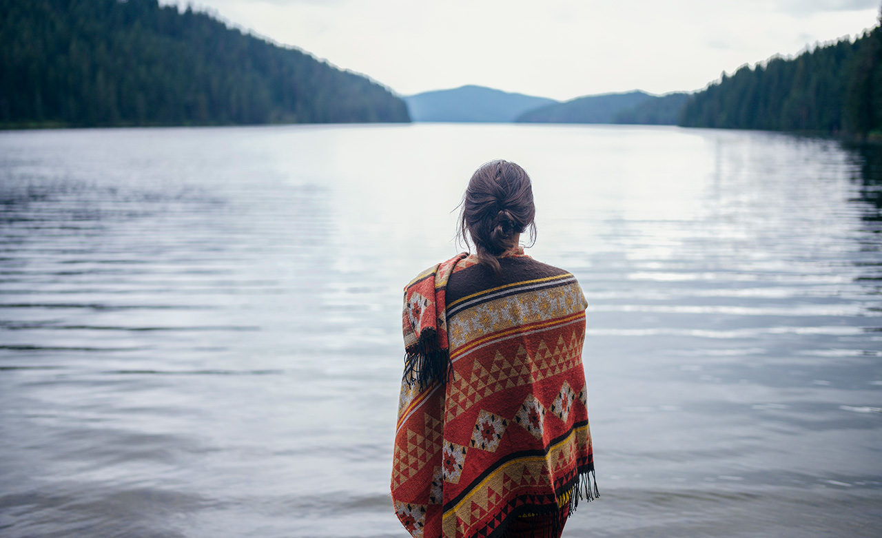 Woman standing in front of mountain lake 