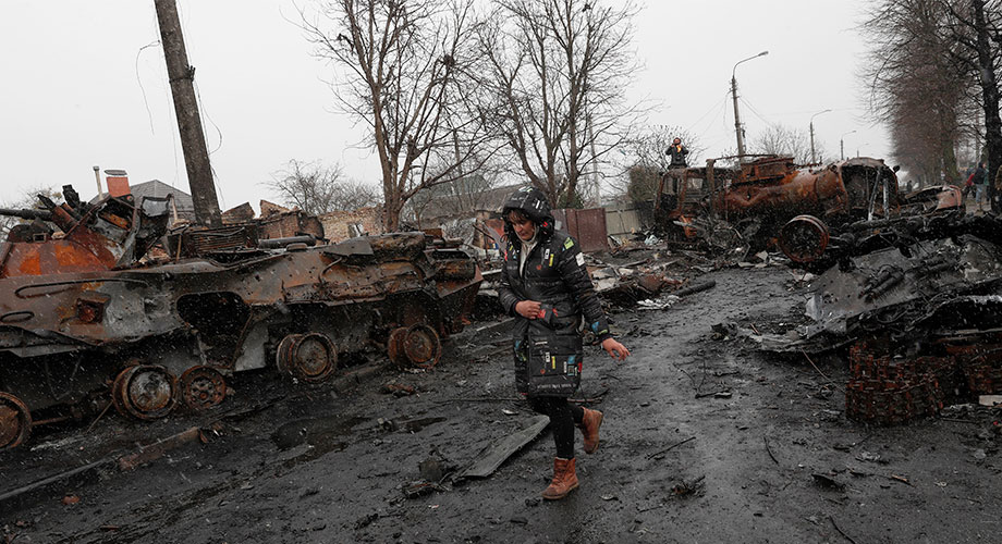 Женщина идет мимо уничтоженной российской военной техники в городе Буча, возвращенном под контроль украинской армии, Украина, 3 апреля 2022 года. EPA-EFE/ATEF SAFADI