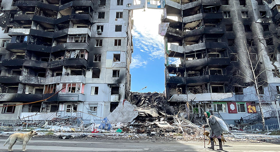2022年4月7日，在乌克兰基辅州布恰地区的博罗江卡小镇，一名老年人拄着拐杖经过遭俄罗斯军队空袭后的公寓大楼废墟，乌克兰军队已重新占领了该地区。