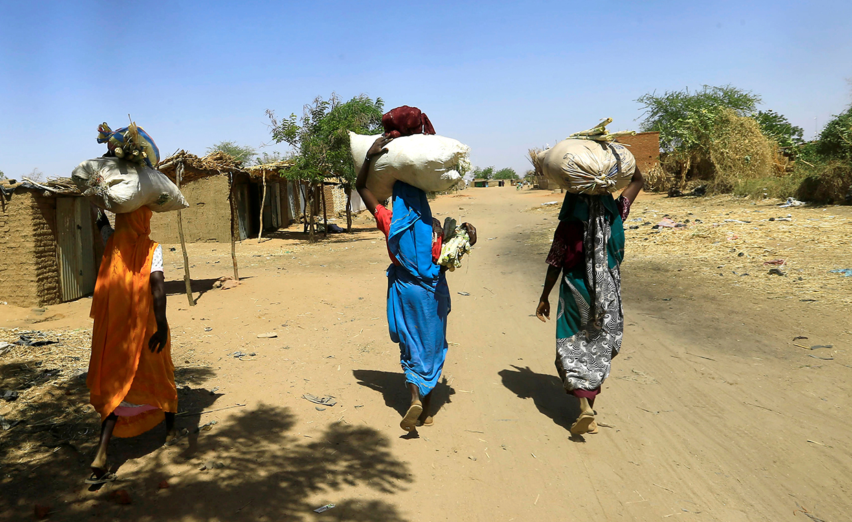 Internally displaced Sudanese women carry bags of farm products on their heads as they walk within the Kalma camp for internally displaced persons (IDPs) in Darfur, Sudan April 25, 2019. 