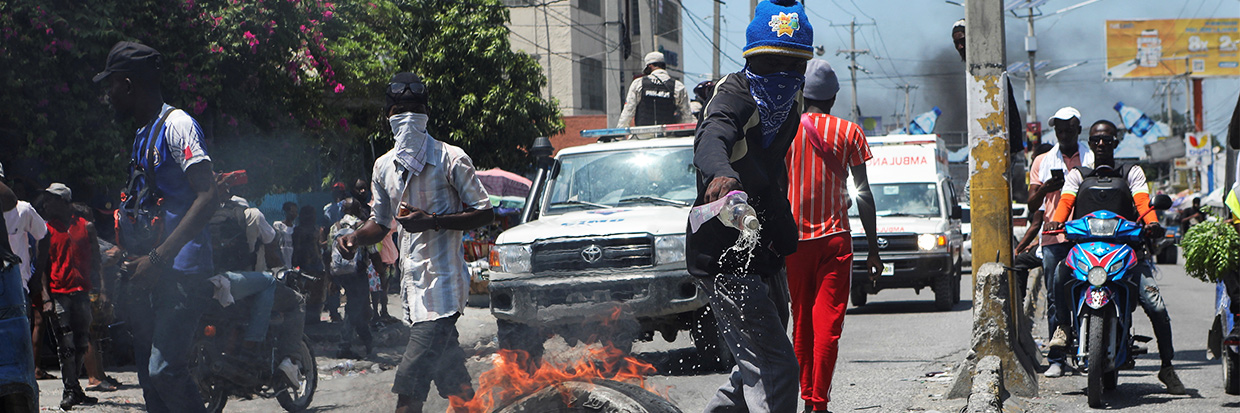 2023年9月17日，海地首都太子港，一名示威者在抗议不安全局势和要求海地总理阿里埃尔·亨利（Ariel Henry）辞职的集会中将液体燃料倒在轮胎上并在路障处将其焚烧。图片来源：路透社/Ralph Tedy Erol