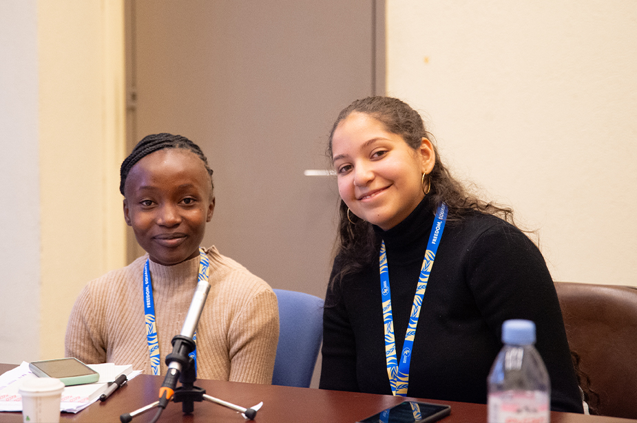 Doris (left) and Anna Katherina (right) sitting at a desk in front of a microphone after an interview on the side lines of the Human Rights 75 forum, December 2023, Geneva, Switzerland. © OHCHR/Irina Popa