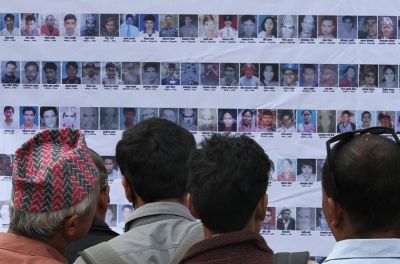 尼泊尔加德满都毛派叛乱期间失踪人员的亲属和当地民众站在一起查看他们的照片。© 欧洲新闻图片社﻿/NARENDRA SHRESTHA