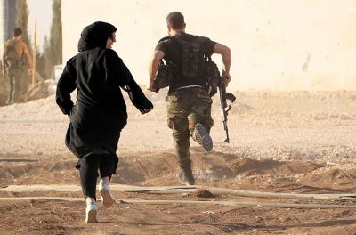 2014年10月10日，在阿勒颇北部乡村对伊斯兰国作战的前线，女记者与一名叛军战士狂奔，躲避狙击手。路透社/Jalal Al-Mamo