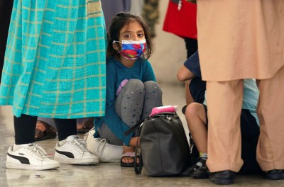فتاة أفغانية تنتظر مع لاجئين آخرين حافلة تقلّهم إلى مركز معالجة الطلبات لدى وصولهم إلى مطار دالاس الدولي في دالاس بفيرجينيا في الولايات المتحدة، 26 آب/ أغسطس 2021. رويترز/ كيفين لامارك.