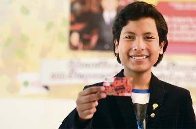 خوسيه كيسوكالا يقف حاملاً بطاقة من مصرف أنشأه في سن السابعة لمساعدة الأطفال الفقراء. © خوسيه كيسوكالا