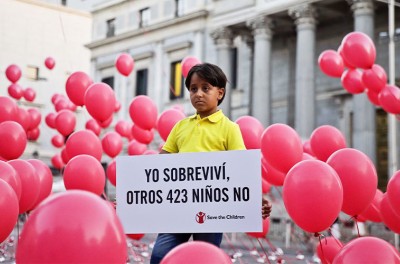 Zaïd, un réfugié syrien de huit ans, pose pour les photographes entouré de ballons tout en tenant une pancarte sur laquelle on peut lire « J’ai survécu, contrairement à 423 autres enfants », lors d’un événement organisé par Save the Children à Madrid, en Espagne. EPA/EMILIO NARANJO