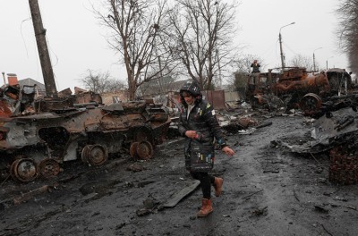 A Ukrainian woman walks pass destroyed Russian military machinery in the areas recaptured by the Ukrainian army in the city of Bucha, Ukraine, 03 April 2022. EPA-EFE/ATEF SAFADI.