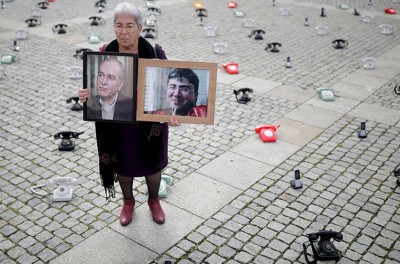 2021年8月28日，在德国柏林，法德瓦·马哈穆德（Fadwa Mahmoud）举着儿子和丈夫的肖像，他们于2012年失踪。多个叙利亚家庭在倍倍尔广场上放置了大约300部固定电话站，以此呼吁各国政府采取更多行动，寻找有关叙利亚被拘留者的下落。路透社／汉尼拔·汉施克（Hannibal Hanschke）