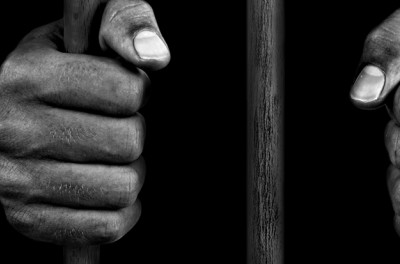 Hands of a prisoner on bars - stock photo - Credits: Getty Images