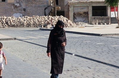 People walk past ruins in Aleppo, Syria, 17 June 2022 © Reuters
