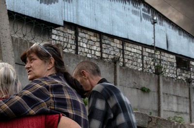 امرأة تعانق والدتها أثناء مراقبة أعمدة من الدخان الأسود تتصاعد من مستودع للسيارات تعرّض لقصف المدفعية الروسية في ليسيتشانسك بلوهانسك، في 28 أيار/ مايو 2022.
