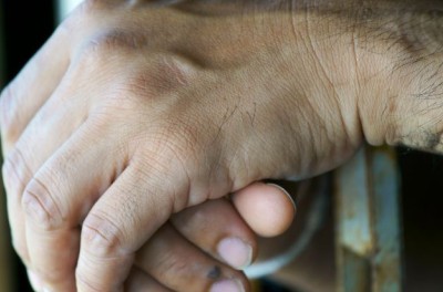 Hand shot of a prisoner behind bars. © Getty Images