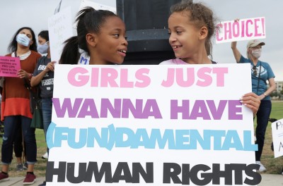 Dos niñas sostienen un cartel mientras las defensoras de los derechos reproductivos de las mujeres participan en la Marcha de las Mujeres en Texas. © Crédito – ©REUTERS/Shelby Tauber