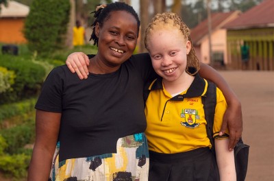 14岁的伊丽莎白·阿耶贝尔（Elizabeth Ayebere）和母亲斯科维娅·恩斯门塔（Scovia Nsimenta）拥抱庆祝她进入一所新学校。©人权高专办供图