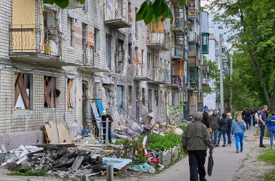 سكان محليون يمرّون أمام مبنى سكني تضرر أثناء القصف على ضواحي خاركيف في أوكرانيا، 25 أيار/ مايو 2022. © الوكالة الأوروبية للصور الصحفية-وكالة الإعلام الإسبانيّة/ سيرغي كوزلوف