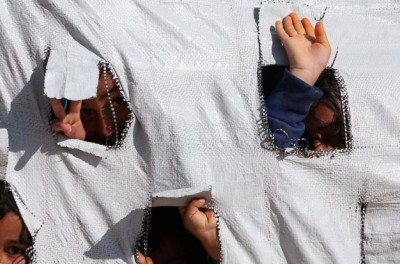 أطفال ينظرون عبر الثقوب في خيمة في مخيم الهول للنازحين في محافظة الحسكة، سوريا، 2 نيسان/ أبريل 2019. © رويترز