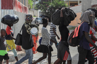 2022年11月19日，因太阳城社区发生帮派战争暴力而流离失所的民众在离开海地首都太子港的雨果·查维斯广场后，走在德尔马斯社区的街道上。©路透社