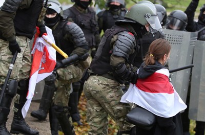Una mujer que porta una bandera histórica blanca, roja y blanca de Belarús es retirada por un agente del orden durante una manifestación en rechazo a los resultados de las elecciones presidenciales en Minsk, Belarús, 8 de noviembre de 2020. © REUTERS/Stringer