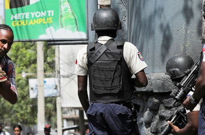 Un homme portant son fils cherche un abri en sortant de l’école alors que la violence des gangs fait rage à Port-au-Prince, Haïti, le 3 mars 2023. © REUTERS/Ralph Tedy Erol