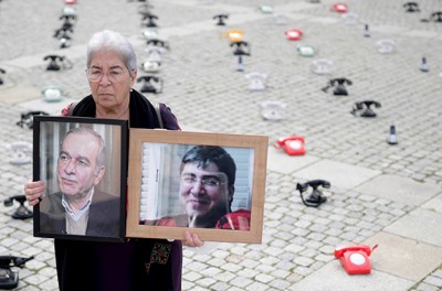 Fadwa Mahmoud holds images of her husband and son, who have been missing since 2012, outside a court in Koblenz, Germany, following the trial of a Syrian intelligence officer in January 2022.  © Thomas Frey/Pool via REUTERS