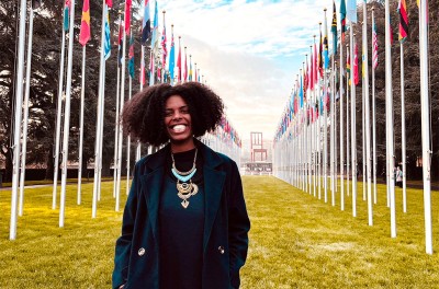 2022年12月，莫妮克·罗德里格斯·多·普拉多（Monique Rodrigues do Prado）站在联合国日内瓦办事处万国宫的断腿椅子雕塑和旗帜前。© 莫妮克·罗德里格斯·多·普拉多