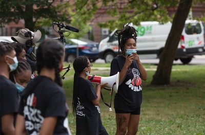 Photo de Bianca Jones aux côtés de jeunes organisateurs à Douglass Park, s’adressant à une foule venue manifester son soutien au changement de nom du parc lors d’un rassemblement pour la relance de la campagne, le 18 juillet 2020. © Kaleb Autman
