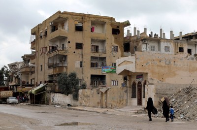 2019年3月31日，叙利亚拉卡市中心，两名叙利亚妇女走过被毁的建筑。©欧新社-埃菲通讯社/AHMED MARDNLI
