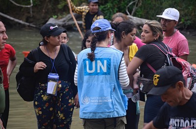 Un trabajador de Derechos Humanos de las Naciones Unidas conversa con personas que llegan al centro de recepción en el lado de Panamá del Tapón del Darién. © Carlos Rodriguez/ROCA
