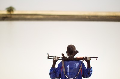رجل يقف متأهّبًا وهو يحمل رشاشًا من طراز AK-47. © رويترز/ جوليان بيهال