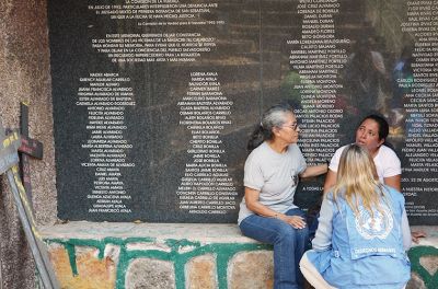 Three women speaking in front of a memorial