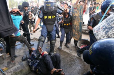 警察脚踢一名倒在地上的男子，菲律宾奎松市，2014年1月 © EPA/ DENNIS M. SABANGAN