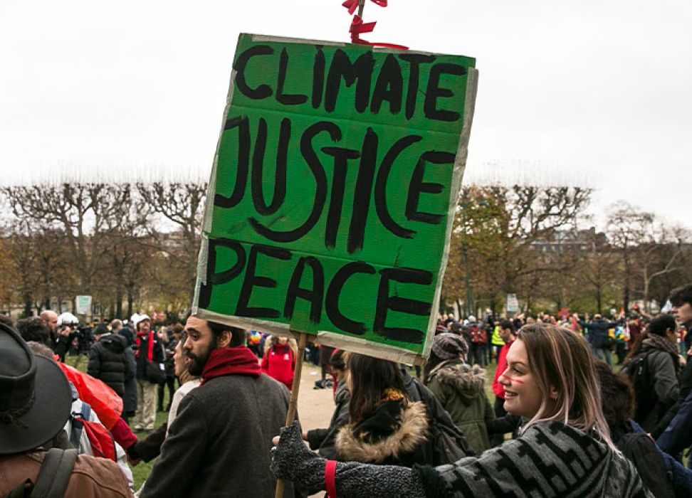 一名妇女在游行队伍中手持呼吁“气候、正义、和平”的标语。Laurent/欧洲新闻图片社