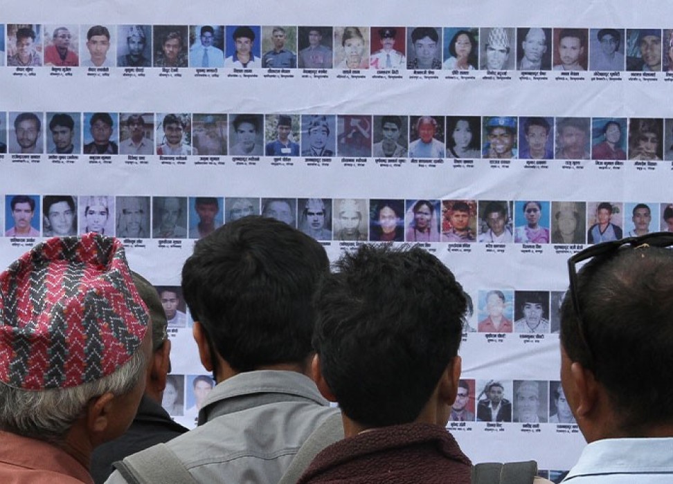 尼泊尔加德满都毛派叛乱期间失踪人员的亲属和当地民众站在一起查看他们的照片。© 欧洲新闻图片社﻿/NARENDRA SHRESTHA