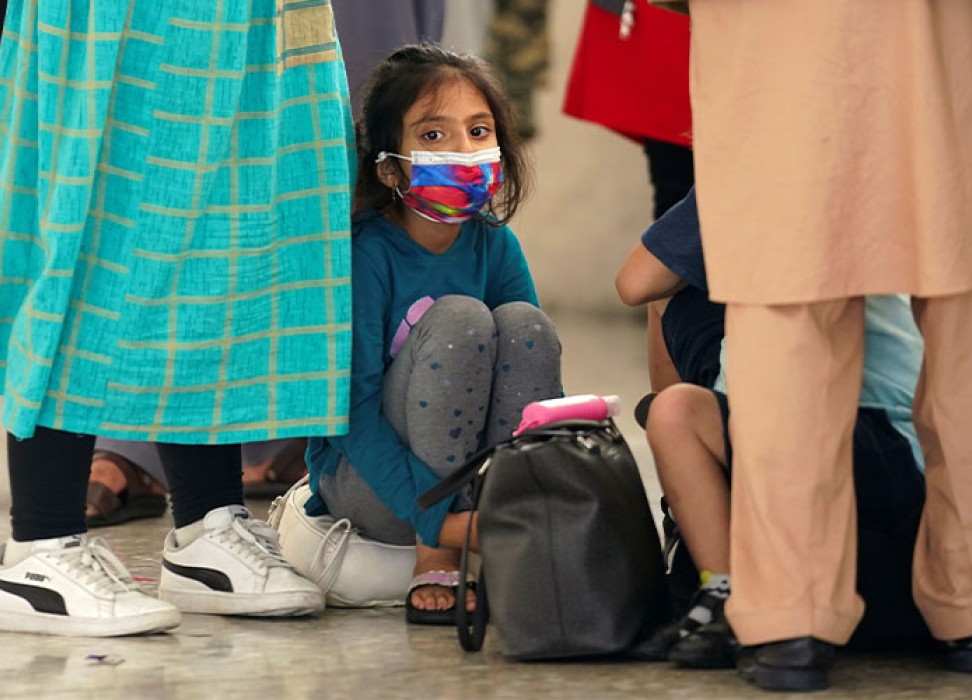 2021年8月26日，在美国弗吉尼亚州杜勒斯市，一名阿富汗女童和其他难民在到达杜勒斯国际机场后，等待公共汽车将她们送往处理中心。路透社/Kevin Lamarque