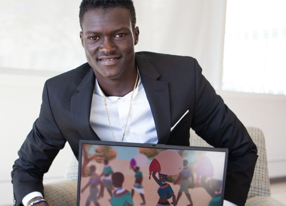 Games designer Lual Mayen poses with a screenshot of one of his games depicting life as a refugee. ©Lual Mayen
