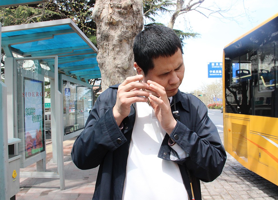 Слепой мужчина использует мобильное приложение, чтобы сесть на автобус, Циндао, провинция Шаньдун, Китай, 5 ноября 2019 г. 