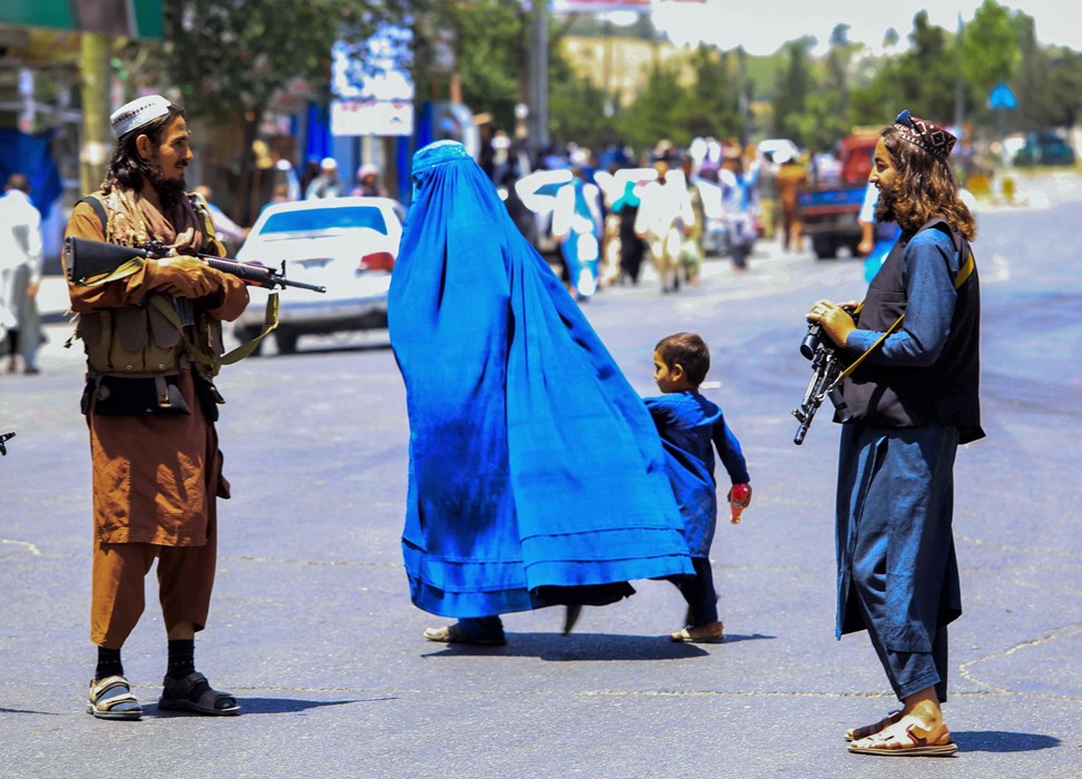أفغانية تمرّ برفقة ابنها أمام عنصرَيْن من طالبان © - الوكالة الأوروبية للصور الصحفية-وكالة الإعلام الإسبانيّة