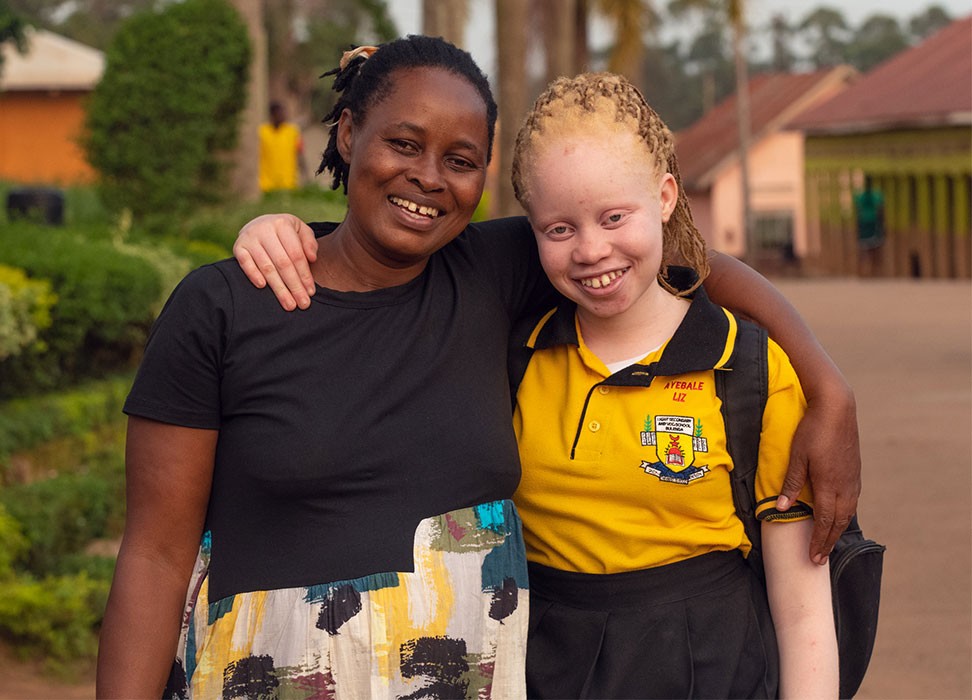 14岁的伊丽莎白·阿耶贝尔（Elizabeth Ayebere）和母亲斯科维娅·恩斯门塔（Scovia Nsimenta）拥抱庆祝她进入一所新学校。©人权高专办供图